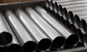 Rury ze stali kwasoodpornej ułożone w pojemniku. Ich gładka, metaliczna powierzchnia odbija światło, tworząc wrażenie czystości i precyzji.