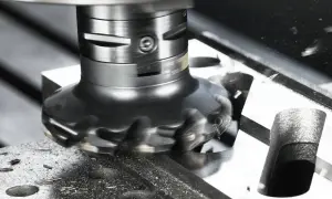 Obrabiarka wykonuje frezowanie czołowe, usuwając materiał z metalowego bloku. Wióry metalu wirują wokół narzędzia.