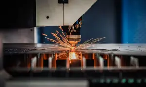 Precyzyjna obsługa maszyn CNC: laser tnie metal, sypiąc iskrami.