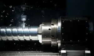 Precyzyjne toczenie gwintów na metalowym wałku w maszynie CNC. Wióry metalu unoszą się w powietrzu.