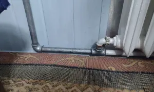 Instalacja grzewcza z metalowymi rurami, pokazująca, jak nagwintować rurę do podłączenia grzejnika.