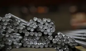Stos metalowych prętów walcowych z gwintem, gotowych do użycia w budowie.