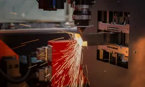 Precyzyjne cięcie metalu przez laser. Iskry sypią się z miejsca obróbki, tworząc widowiskowy otwór technologiczny.