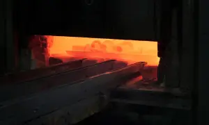Żar rozgrzanego pieca, gdzie odbywa się hartowanie na wskroś. Metalowe elementy wchodzą w płomienie.