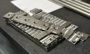 Stos precyzyjnie wykonanych elementów metalowych, świadczących o frezowaniu wielkogabarytowym.