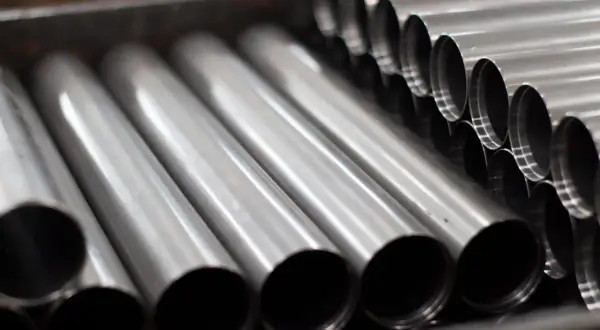Rury ze stali kwasoodpornej ułożone w pojemniku. Ich gładka, metaliczna powierzchnia odbija światło, tworząc wrażenie czystości i precyzji.