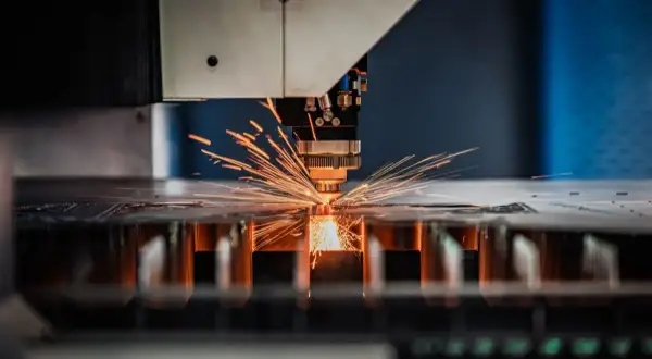 Precyzyjna obsługa maszyn CNC: laser tnie metal, sypiąc iskrami.