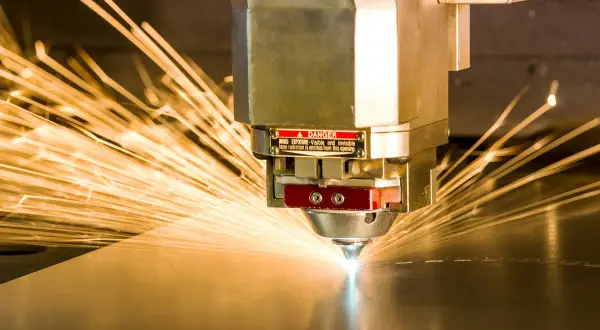 Precyzyjne cięcie metalu przez laser przemysłowy, iskry rozchodzą się na boki.