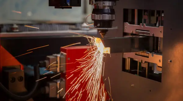 Precyzyjne cięcie metalu przez laser. Iskry sypią się z miejsca obróbki, tworząc widowiskowy otwór technologiczny.