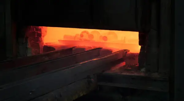 Żar rozgrzanego pieca, gdzie odbywa się hartowanie na wskroś. Metalowe elementy wchodzą w płomienie.