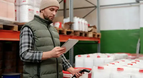 Pracownik magazynu sprawdza stany magazynowe, skanując produkty tabletem.