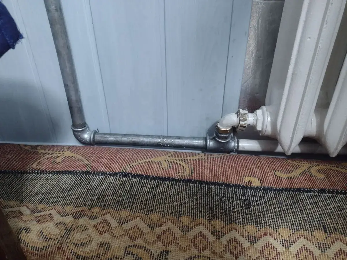 Instalacja grzewcza z metalowymi rurami, pokazująca, jak nagwintować rurę do podłączenia grzejnika.