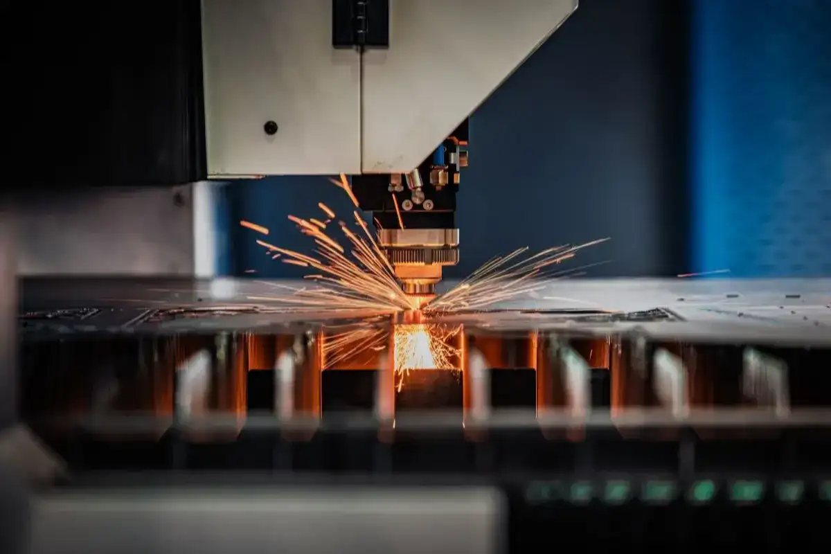 Precyzyjna obsługa maszyn CNC: laser tnie metal, sypiąc iskrami.