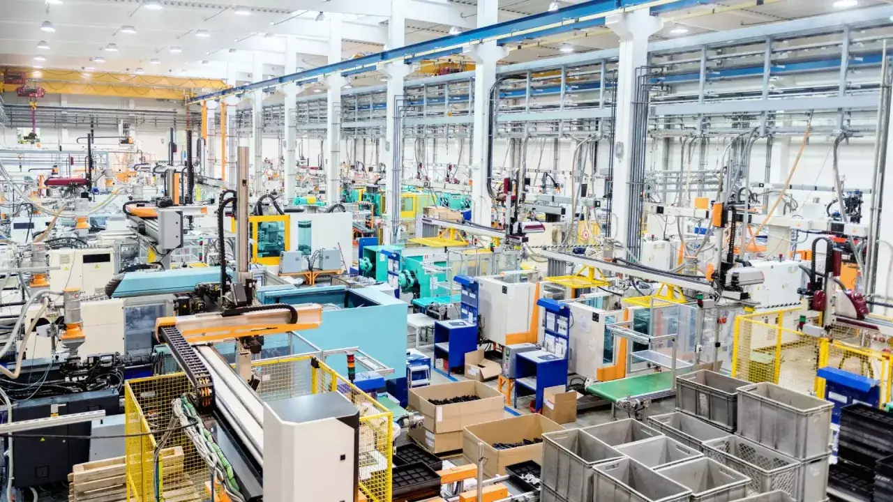 Nowoczesna hala produkcyjna z maszynami i taśmociągami, gdzie działają zaawansowane systemy zarządzania produkcją.