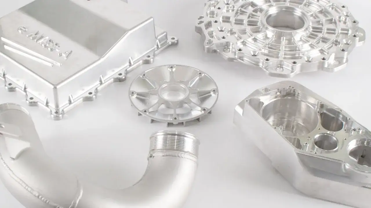 Precyzyjnie obrobione elementy z aluminium 6061, w tym obudowa z logo, koło zębate i części silnika, prezentują zaawansowane możliwości obr&oacute;bki CNC.
