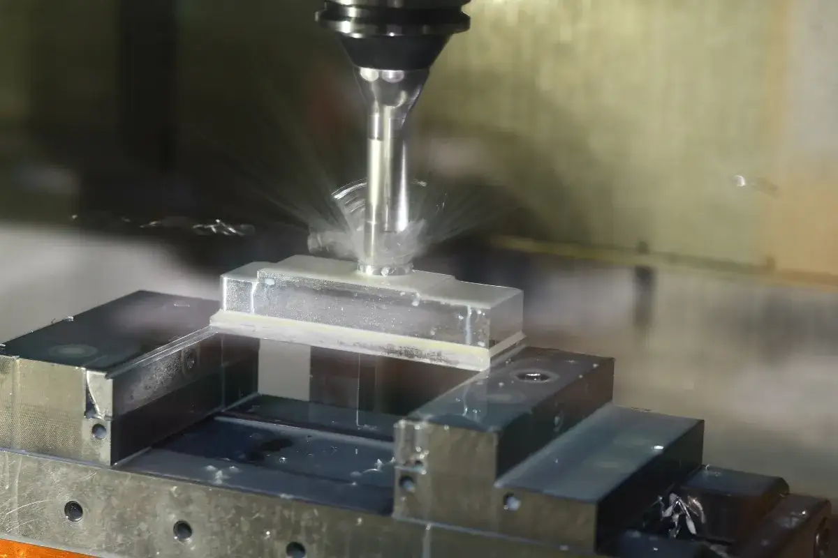 Precyzyjna obr&oacute;bka aluminium na maszynie cnc. Wi&oacute;ry i chłodziwo rozpryskują się podczas frezowania.