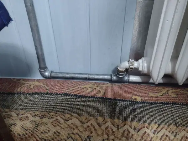 Instalacja grzewcza z metalowymi rurami, pokazująca, jak nagwintować rurę do podłączenia grzejnika.