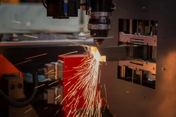 Precyzyjne cięcie metalu przez laser. Iskry sypią się z miejsca obróbki, tworząc widowiskowy otwór technologiczny.