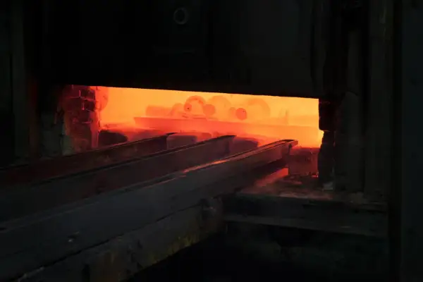 Żar rozgrzanego pieca, gdzie odbywa się hartowanie na wskroś. Metalowe elementy wchodzą w płomienie.